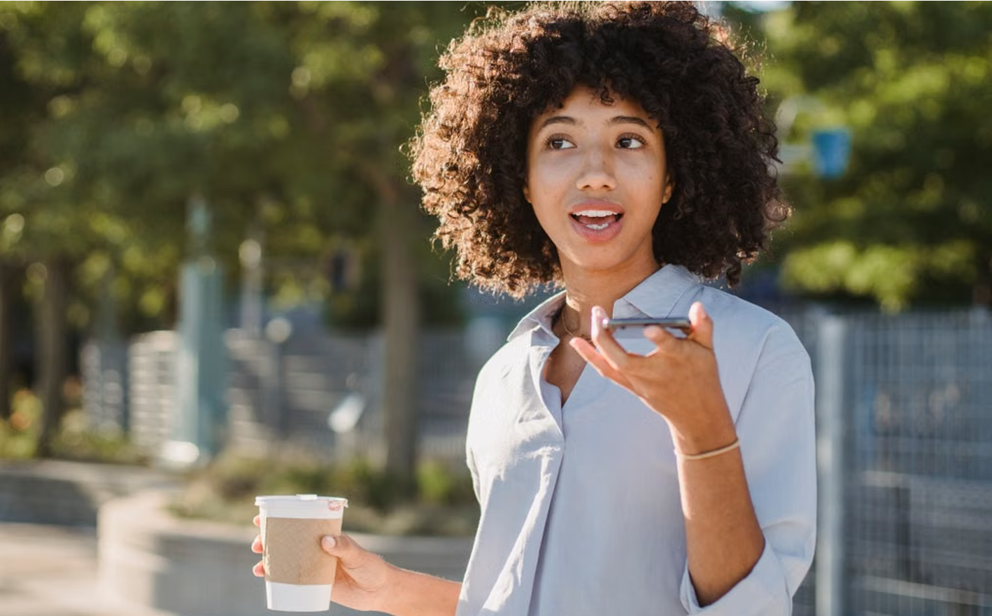 A woman speaking a voice note into her phone